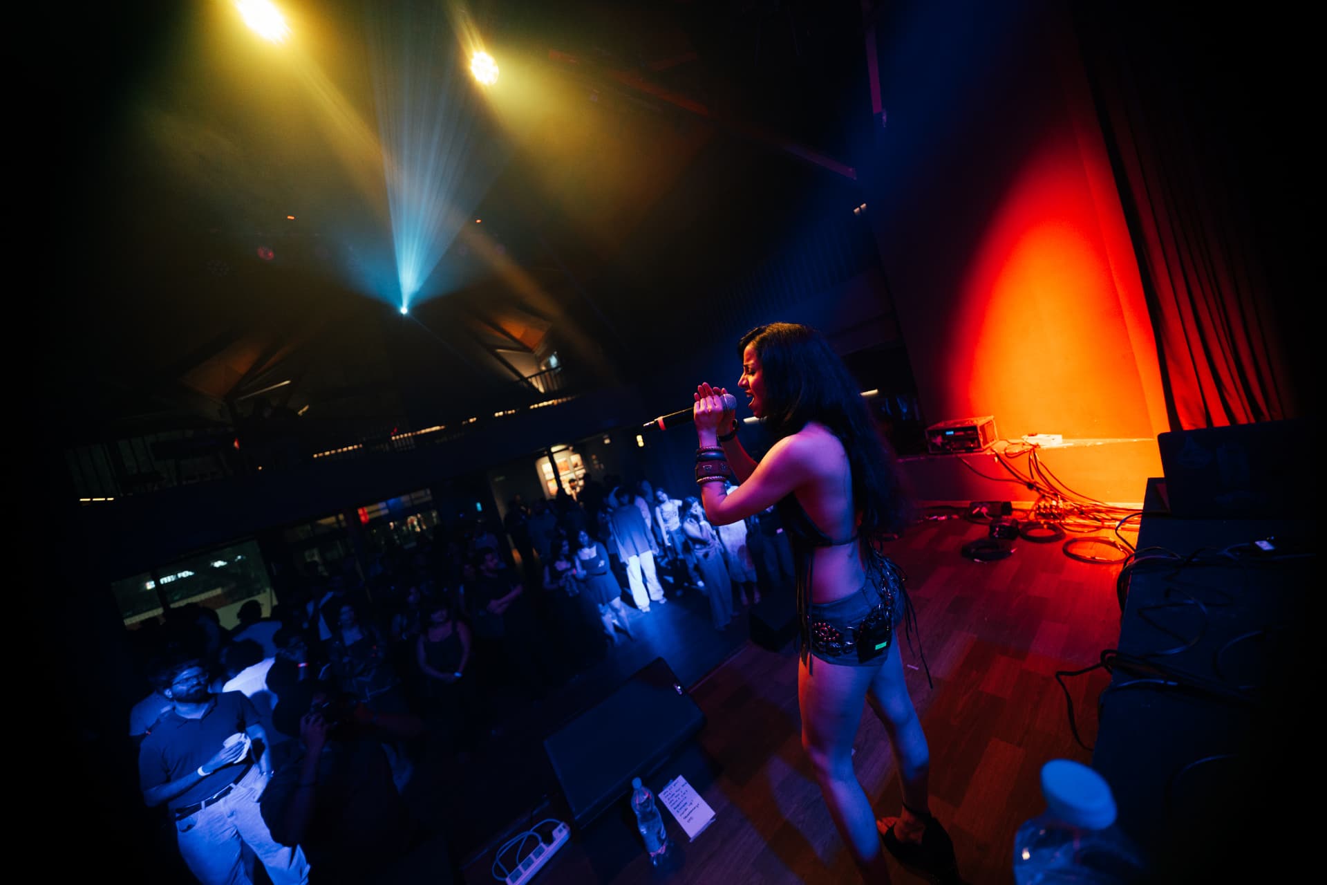 Vocalist seen from above singing under warm spotlights and red stage light