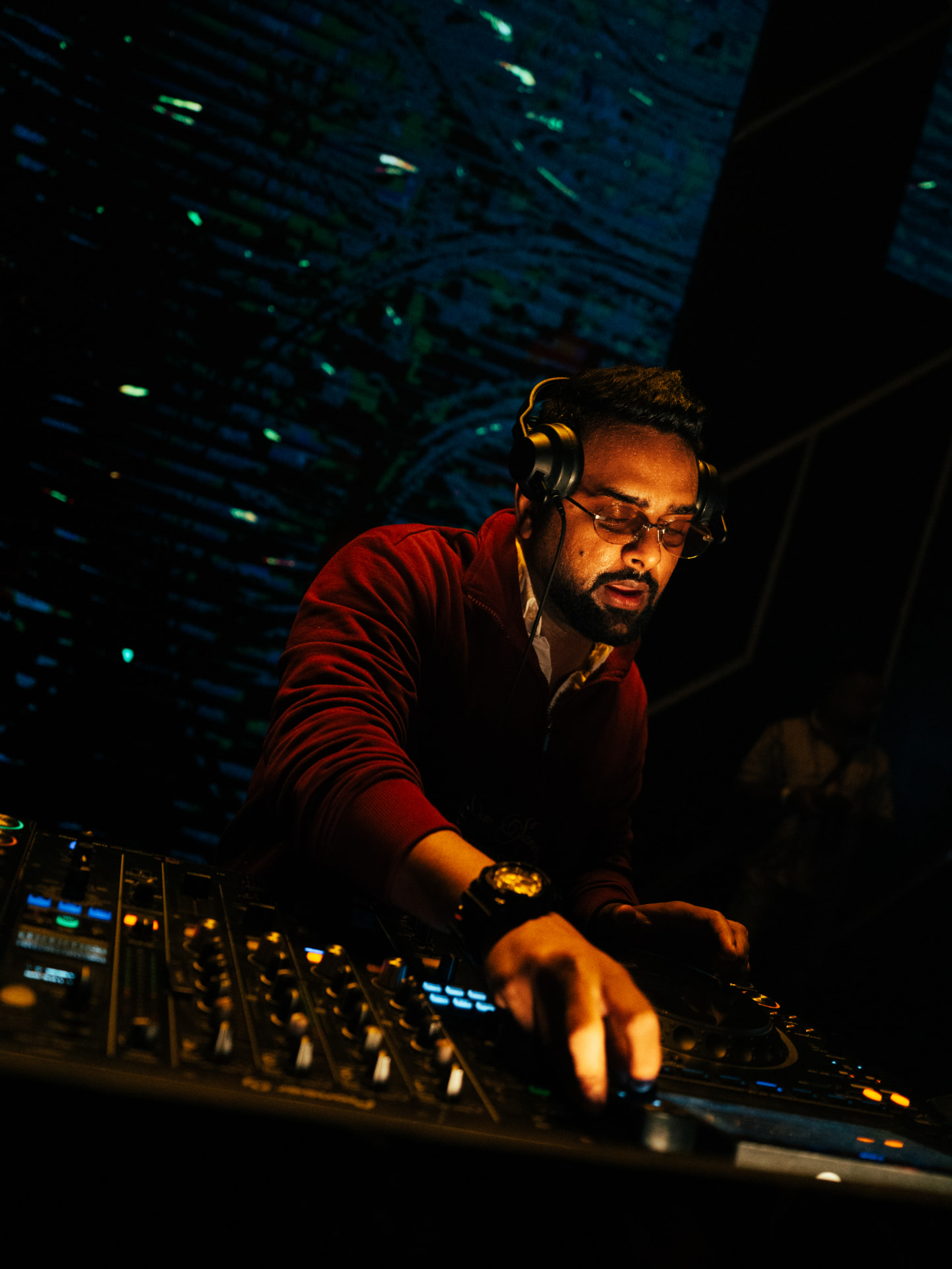 DJ with headphones lost in the mix under deep red club light
