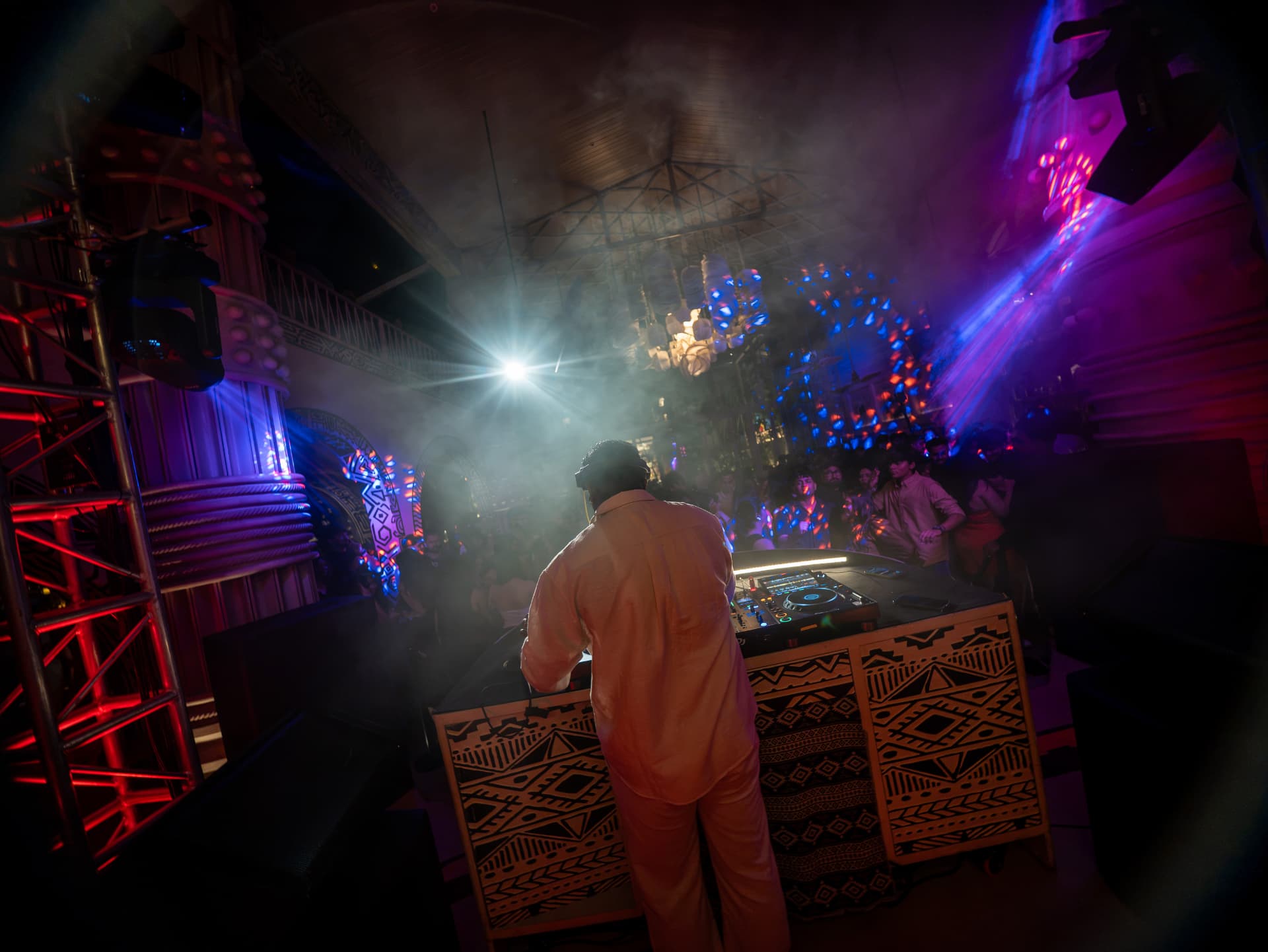 View from behind the DJ toward a packed dance floor