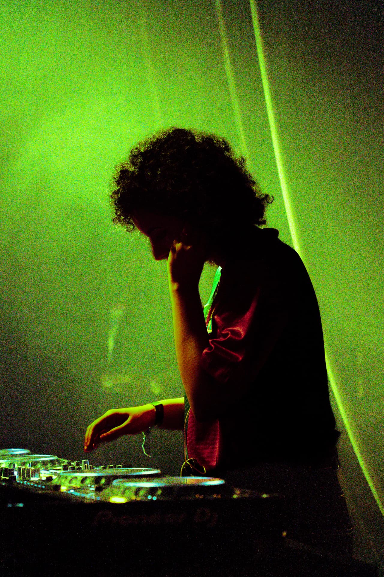 Performer silhouetted in green light while reaching toward the mixer