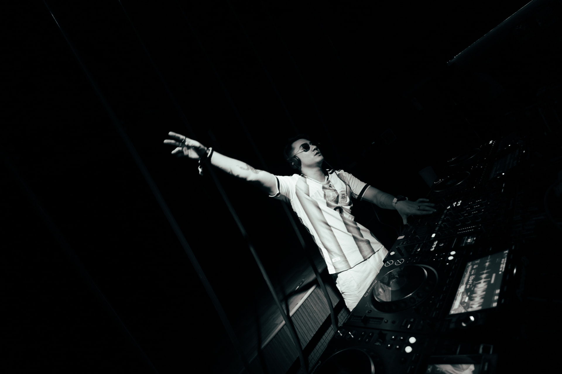 Black-and-white shot of a DJ with an arm outstretched over the decks