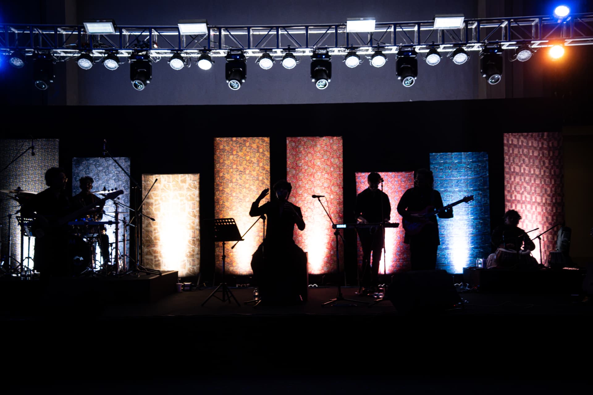 Band silhouetted on a stage backed by glowing patterned panels