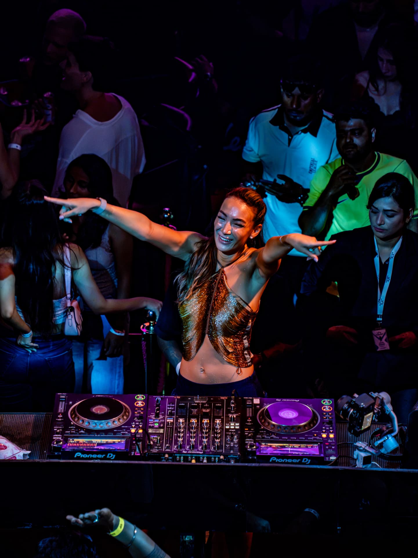 DJ performing with outstretched arms in a crowded club