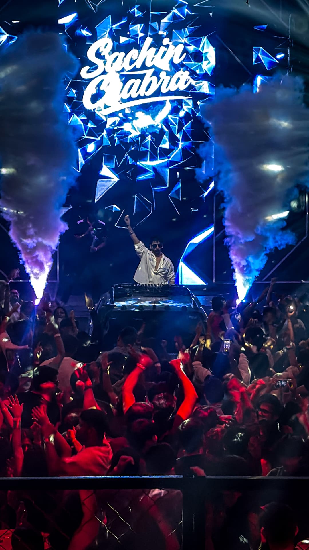 Concert crowd beneath a blue-lit stage and Sachin Jabra display
