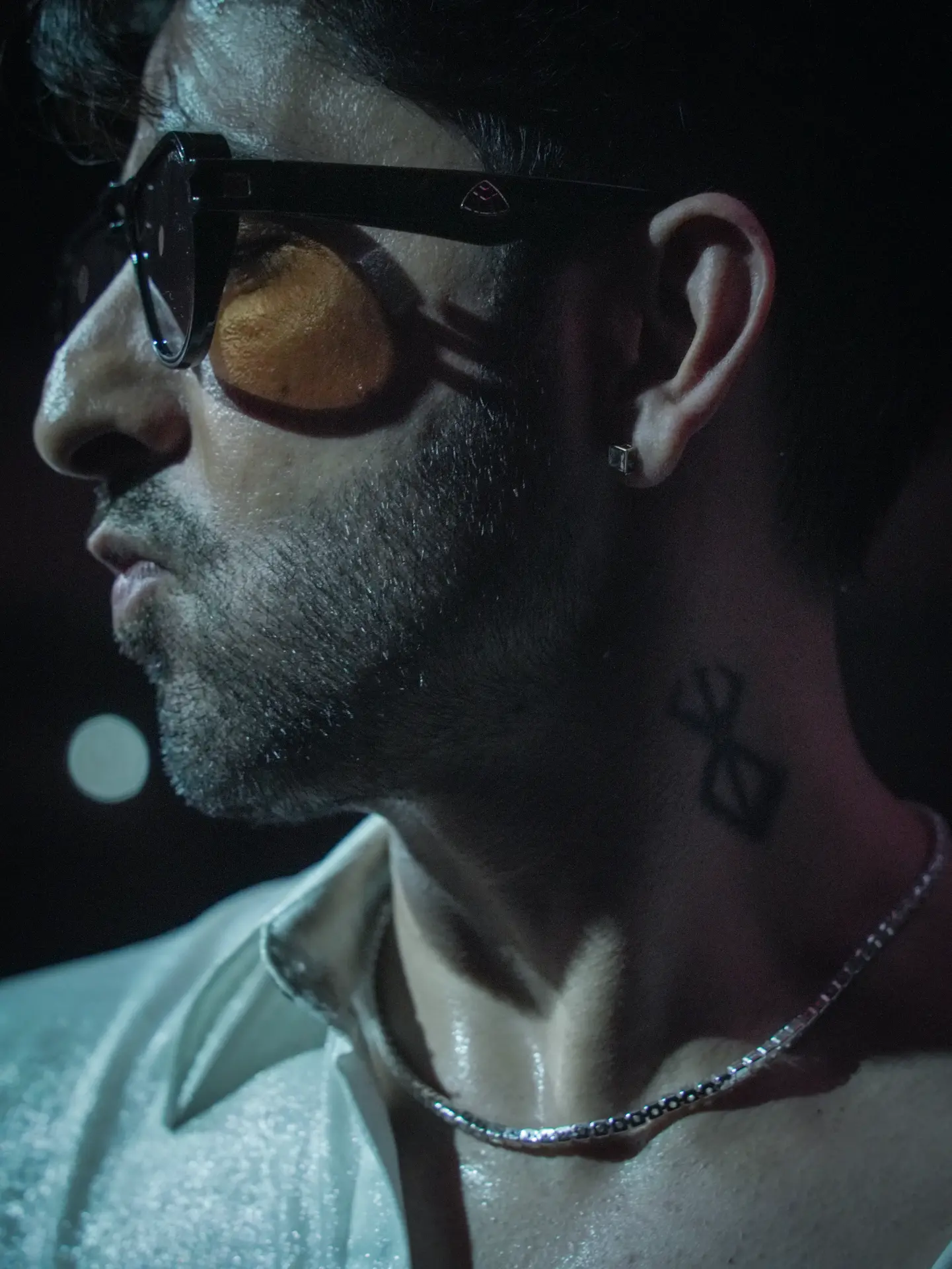 Close-up portrait of a man wearing sunglasses in dramatic light