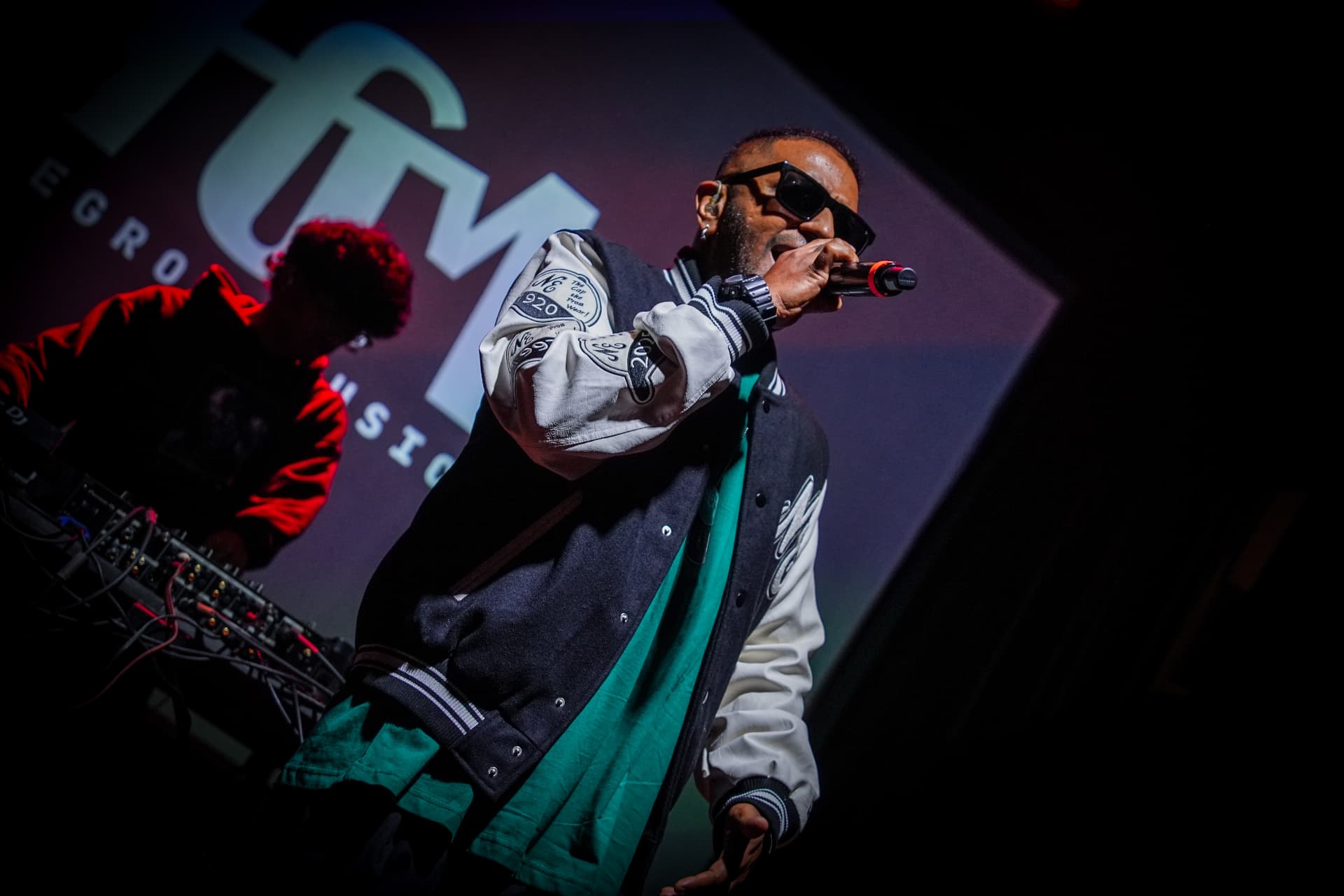 Singer in sunglasses performing with a microphone on stage