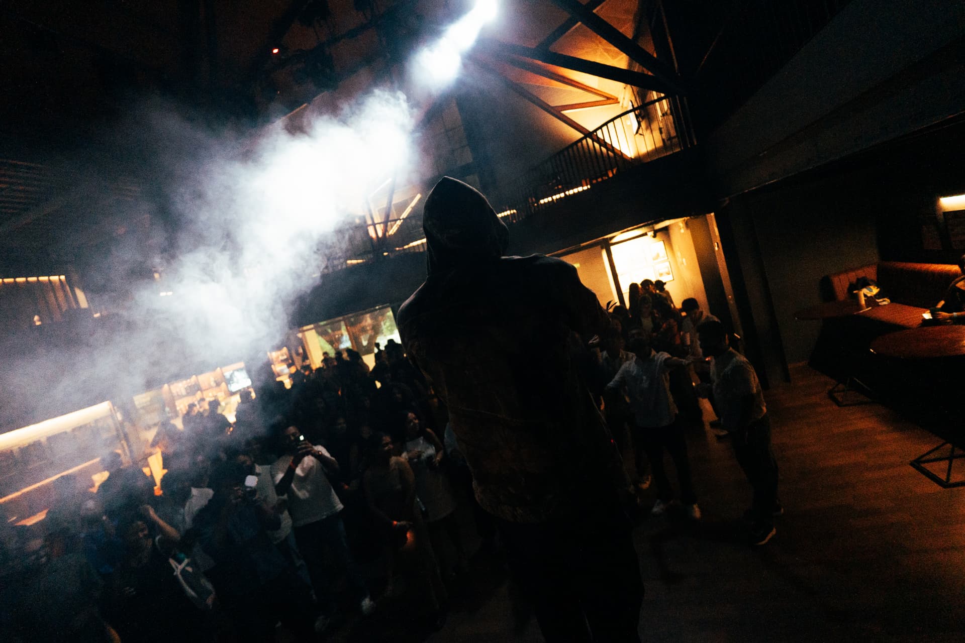 Hooded performer on a smoke-filled stage looming over the crowd