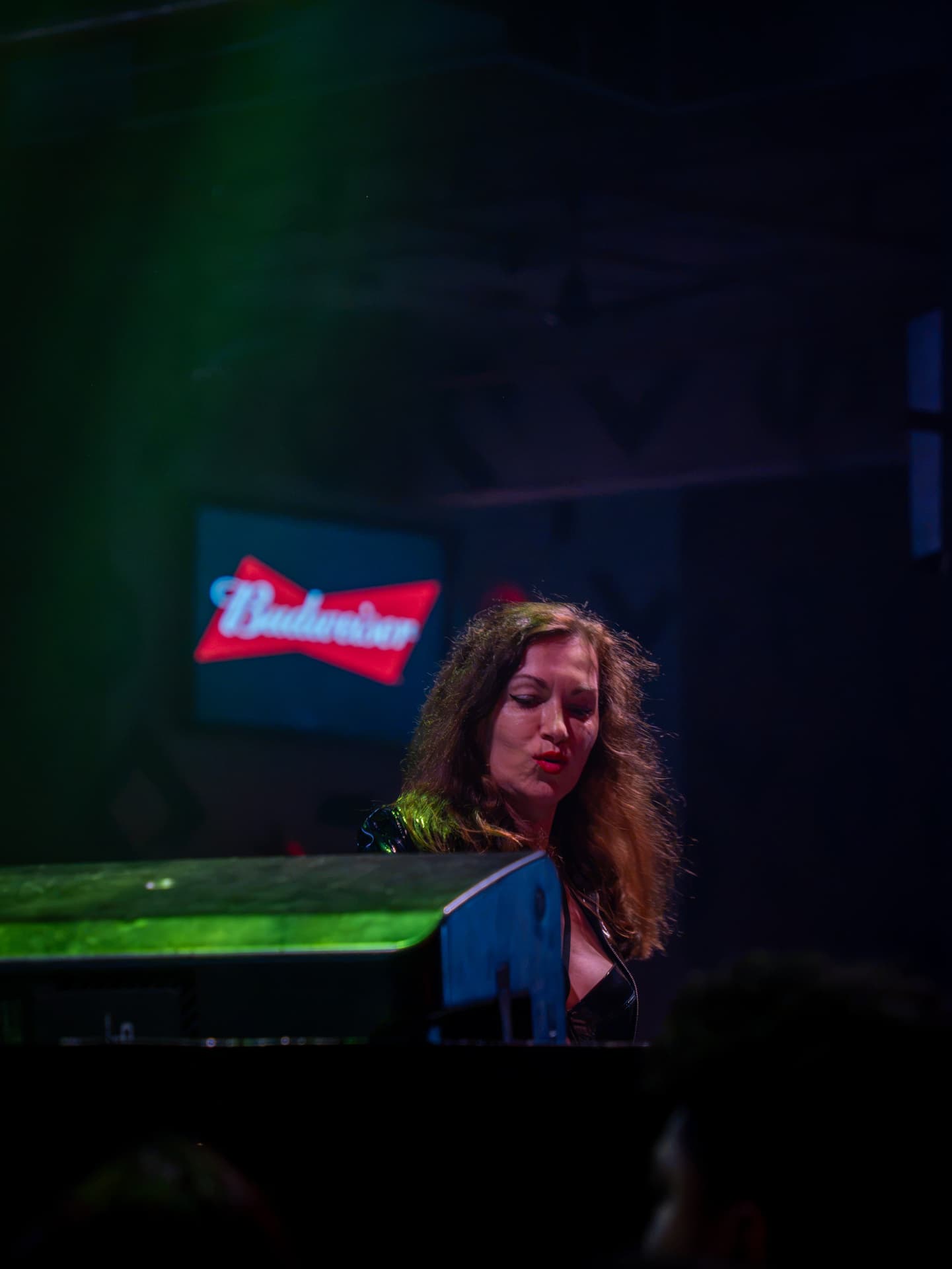 DJ performing behind the decks in a club lit by green stage lights